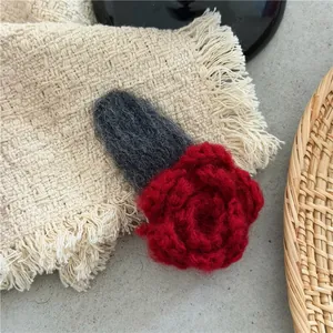 Detailed macro view of handmade red crochet rose flower hair clip with grey BB base