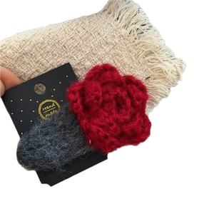 Handmade red crochet flower hair clip with grey leaf on a black display card