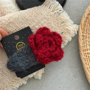 Handmade red crochet rose hair clip with dark grey knit base on a golden dot card