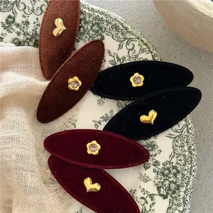 Macro view of vintage velvet oval hair clips with golden heart and floral rhinestone details
