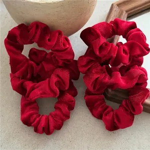 Set of four red velvet scrunchies with pleated texture for elegant hair styling