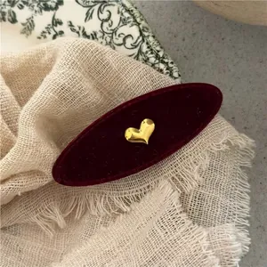 Detail of vintage red velvet oval hair clip with gold 3D heart and floral backdrop