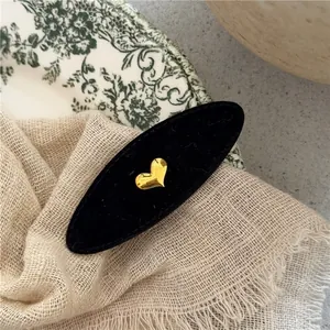 Detail of vintage black velvet oval hair clip with gold heart and rhinestone accents