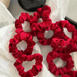 Detailed view of multiple dark red velvet scrunchies with soft texture and elastic bands