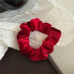 Close-up of red velvet scrunchie showing detailed vertical ribbed texture and soft fabric
