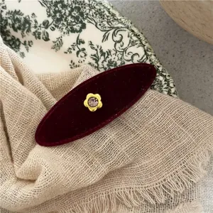 Detail of vintage burgundy velvet hair clip with gold flower rhinestone centerpiece