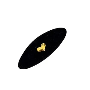 Golden heart-shaped hair clip with polished finish on a black velvet display pad