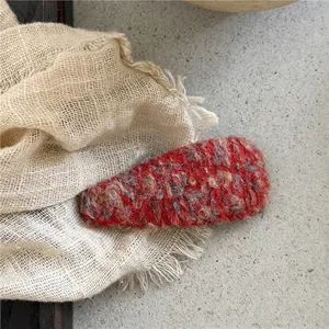 Macro shot of a red wool knitted teardrop hair clip with heavy textured fabric detail