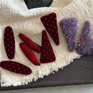 Red polka dot velvet hair clips and purple plush barrettes on a textured fabric