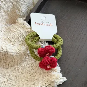 Nahaufnahme der roten Häkelblumen-Haargummis mit rosa Strass auf handgemachter Karte