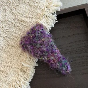 Detail of a purple textured knit triangle hair clip with subtle gold thread accents