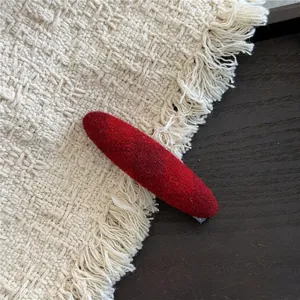 Detailed view of red velvet oval hair clip showing high-quality flocked texture and finish