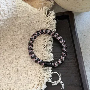 Détail d'élastiques tressés avec soie métallique et boucle en résine sur un plateau