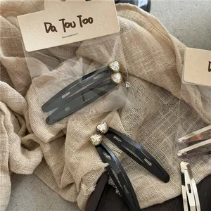 Detalle de pinzas para el pelo de corazón negro mate con cristales y bordes oro