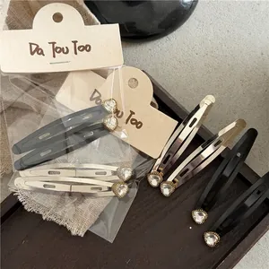 Pinzas para el cabello en metal plateado con pedrería de corazón sobre bandeja madera