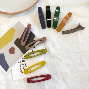 Detailed view of Morandi color geometric hair clips on a soft textured fabric background