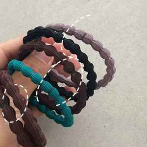Detailed macro of high-elasticity wavy fabric hair ties in vintage dark color palette