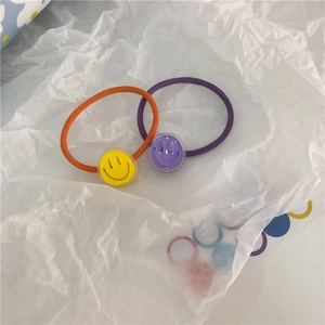 Detail of high-elasticity hair ties with orange and purple smiley face pendants