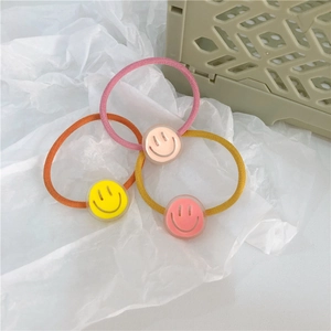 Close-up of three cute smiley face hair ties in yellow, pink and orange colors