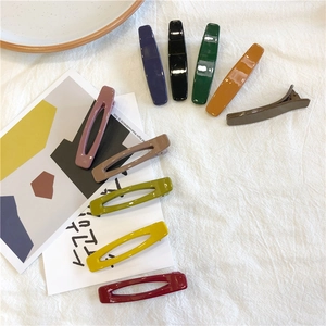 Close-up of vibrant resin hair clips in various geometric shapes on white fabric