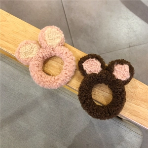 Detail van zachte pluchen berenoor haarelastiekjes in roze en bruin op een houten rekje