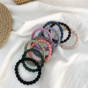 Close-up of colorful seamless wave hair ties on a soft white linen fabric background