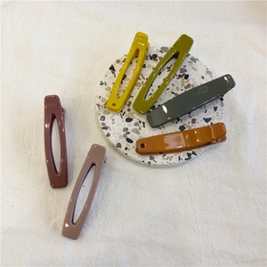 Minimalist geometric hollow hair clips in six colors on a terrazzo plate