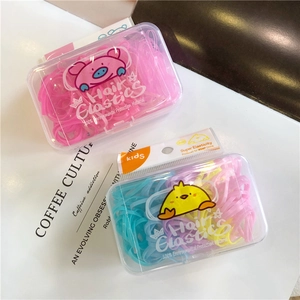 Detail of colorful children hair ties in cute pig and chick themed storage boxes