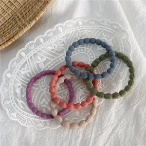 Detail of five seamless high-elastic hair ties in various Morandi colors on lace
