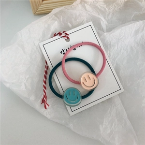 Close-up of pink and green cartoon smiley face hair ties on display card