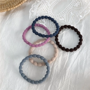 Close-up of wavy elastic hair bands in dark tones with textured pearl knit design