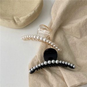 Close-up of elegant black and transparent hair claws with row of white pearl embellishments