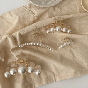 Set of four French vintage pearl hair claws on a textured beige linen fabric