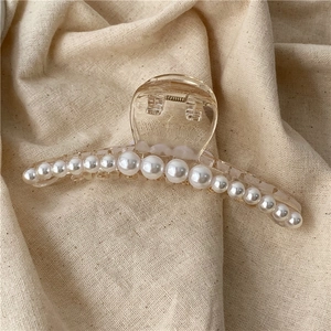 Macro shot of an amber plastic hair claw clip with elegant pearl embellishments