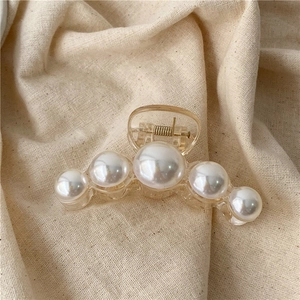 Detail view of large pearl hair claw clip in transparent yellow resin with gold spring
