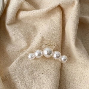 Detail of elegant pearl hair claw clip with 5 gradient pearls on transparent acrylic base