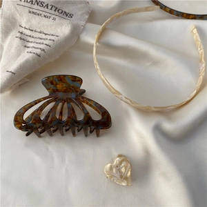 Elegant tortoiseshell acetate hair claw and cream headband set on minimalist fabric