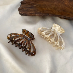 Detail of tortoise shell and marble acetate hollow fan-shaped hair claw clips on white silk
