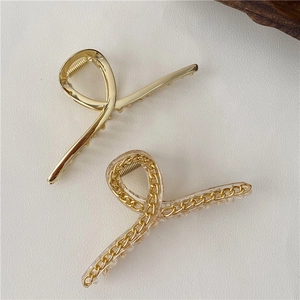 Dettaglio di un fermaglio per capelli in metallo dorato e una clip a catena trasparente