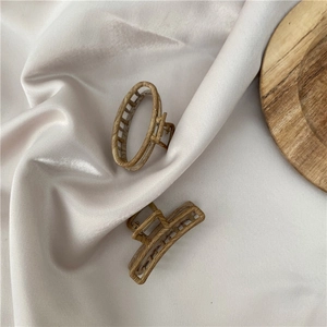 Close-up of wood grain alloy hair clips in oval and rectangle shapes on beige silk