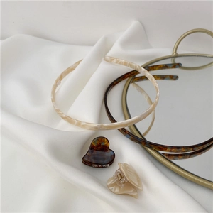 Detail view of acetate heart hair clips and minimalist headbands on white fabric