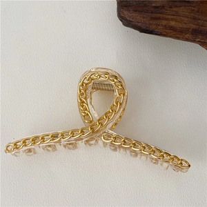 Dettaglio di grande molletta per capelli in acrilico con catena in metallo dorato