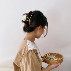 Pinza per capelli incrociata minimalista in metallo dorato opaco su un elegante chignon