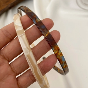 Detail of marble and tortoiseshell acetate headbands held by hand for texture