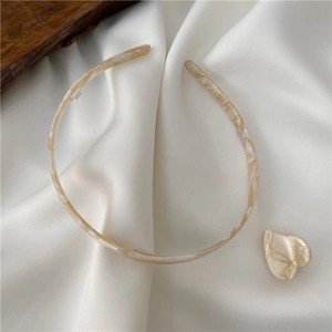 Detail of marble pattern cellulose acetate headband on white silk with non-slip teeth