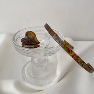 Detail view of acetate hairband and heart mini clip with amber tortoise shell pattern