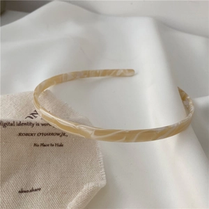Detailed shot of yellow acetate headband with marble texture on minimalist fabric