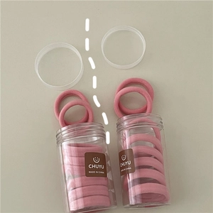 Pink elastic hair ties in a clear container with a minimalist label for women