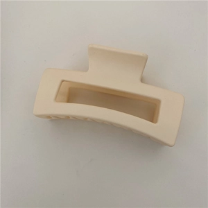 Detail view of a matte cream rectangular hair claw clip with geometric hollow design