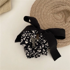 Detail of elegant bow scrunchie with black fabric and leopard print pattern for hair styling